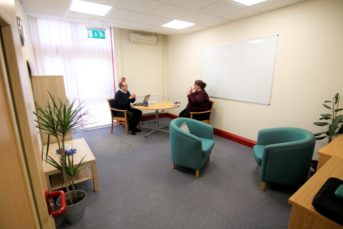 Two people sat in Wren meeting room at Living Options Devon signing in British Sign Language